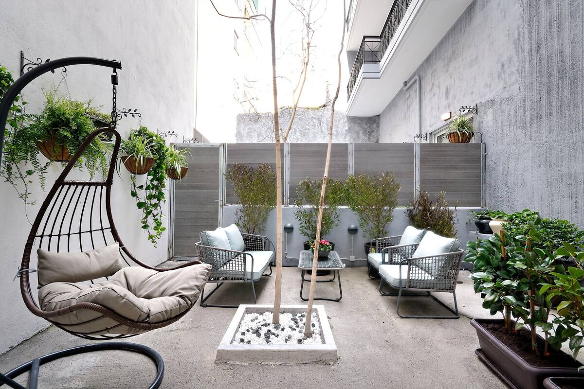 Un patio con una hamaca colgante, dos sofás, una mesita y plantas en macetas.