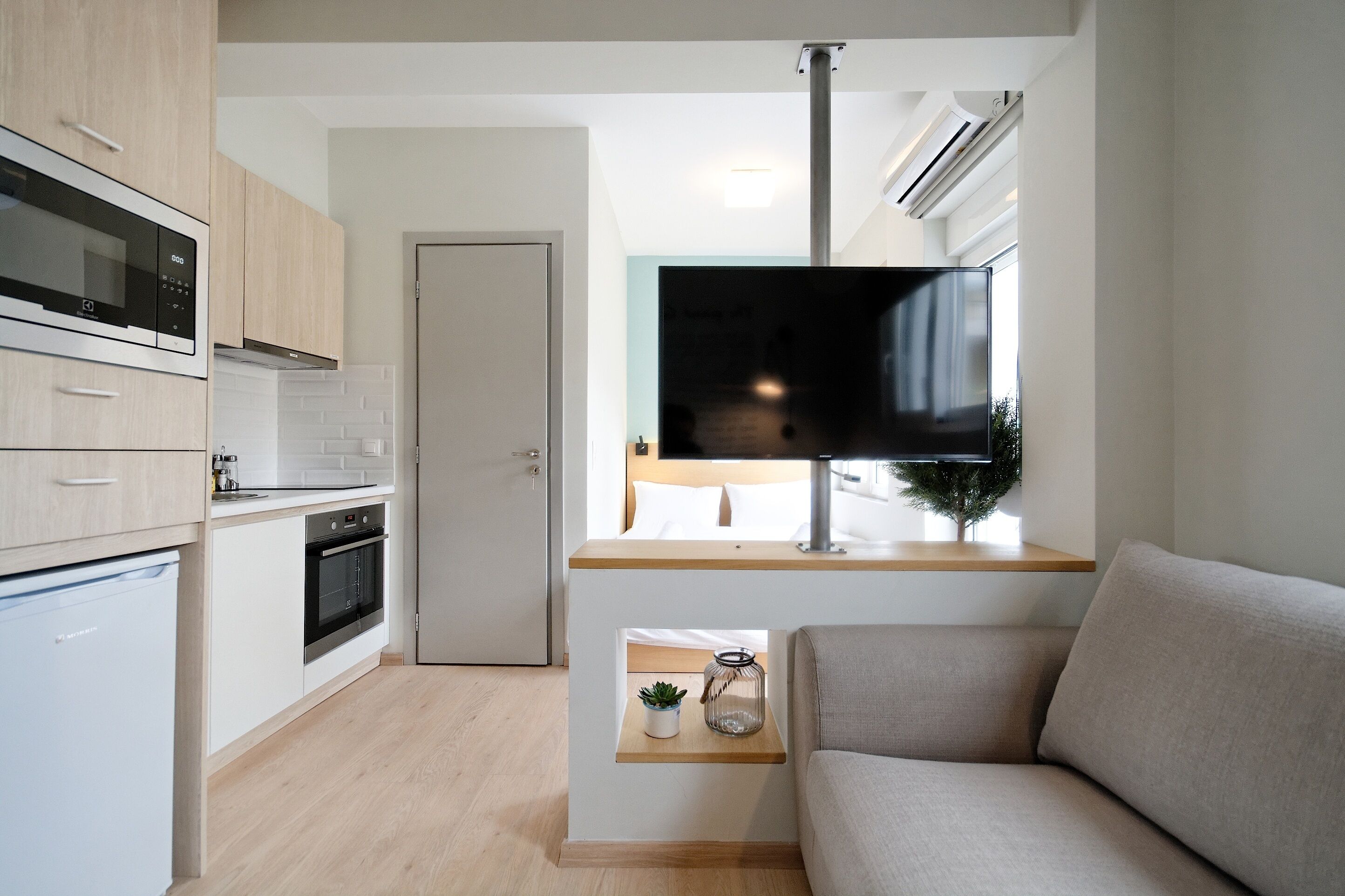 Une cuisine moderne dotée d’appareils électroménagers intégrés, un coin repas avec un téléviseur à écran plat et un espace salon confortable avec un canapé et une table d’appoint.