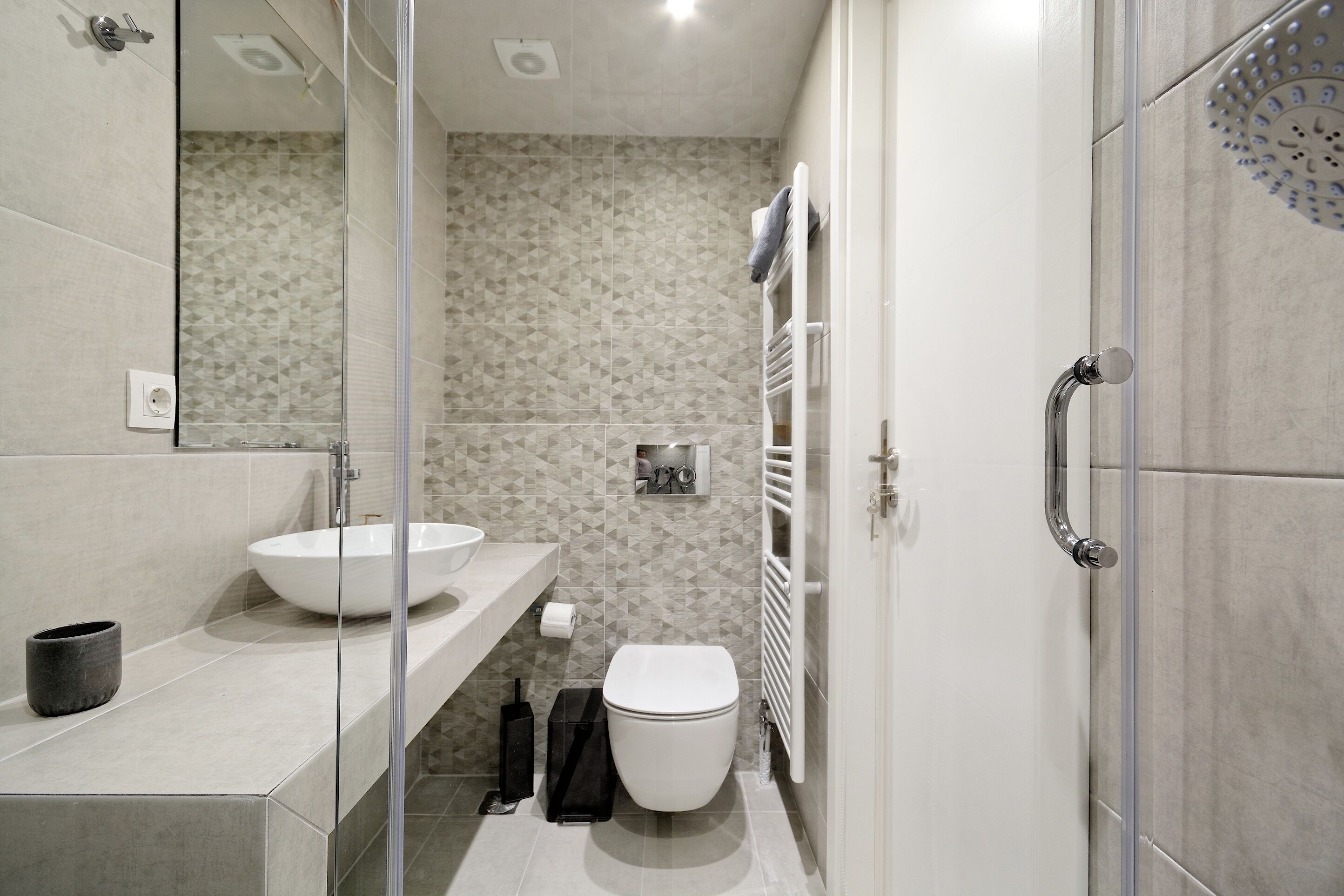 Un bagno moderno con box doccia in vetro, un lavandino bianco e un water.