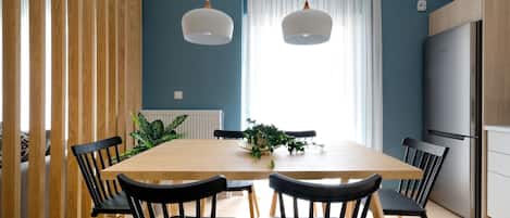 A modern kitchen with a wooden table, black chairs, and a built-in refrigerator.