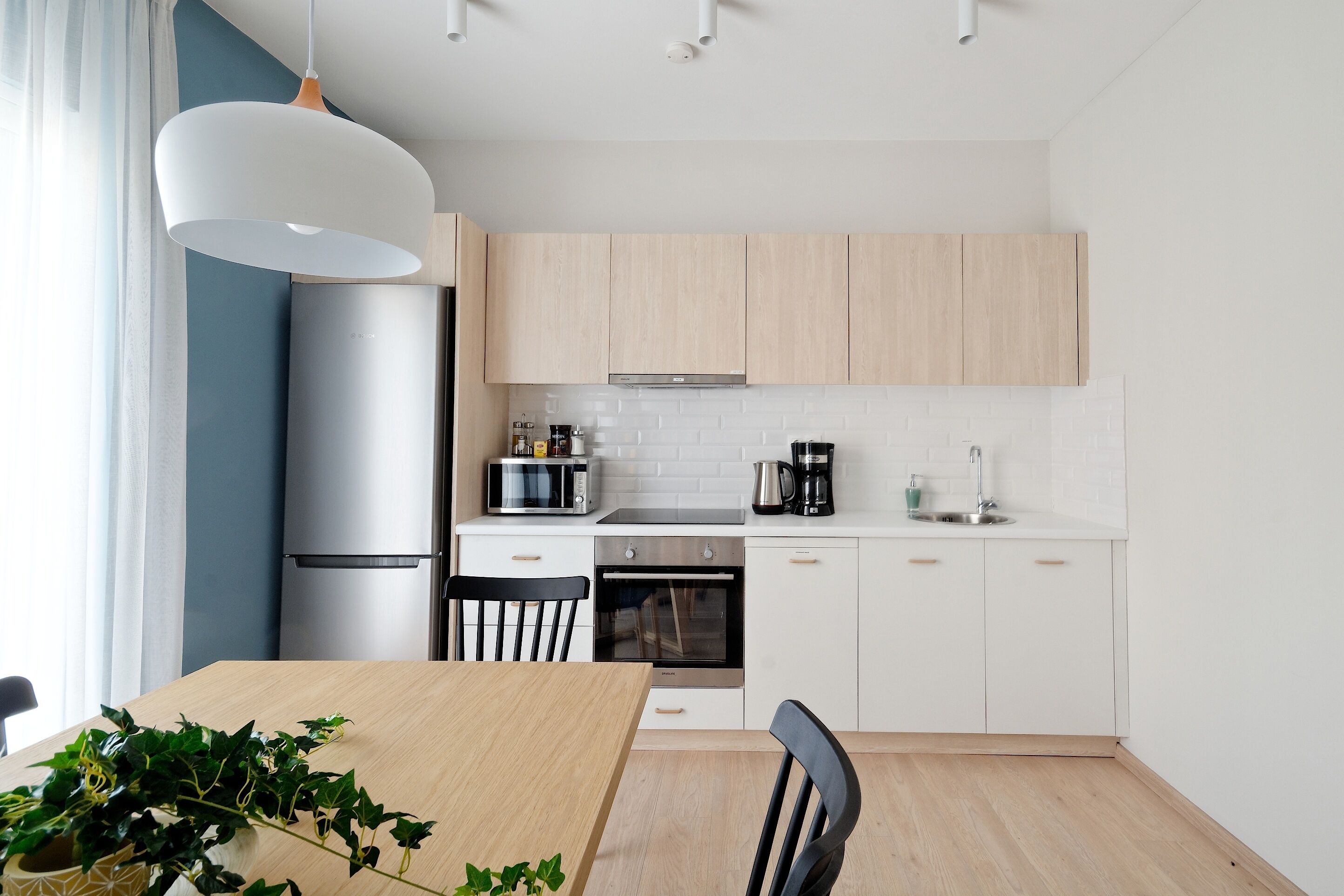 A modern kitchen with white cabinets, a microwave, oven, and a coffee maker.