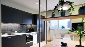 Una cocina moderna con armarios oscuros, salpicadero de azulejos y un área de comedor con mesa y sillas.