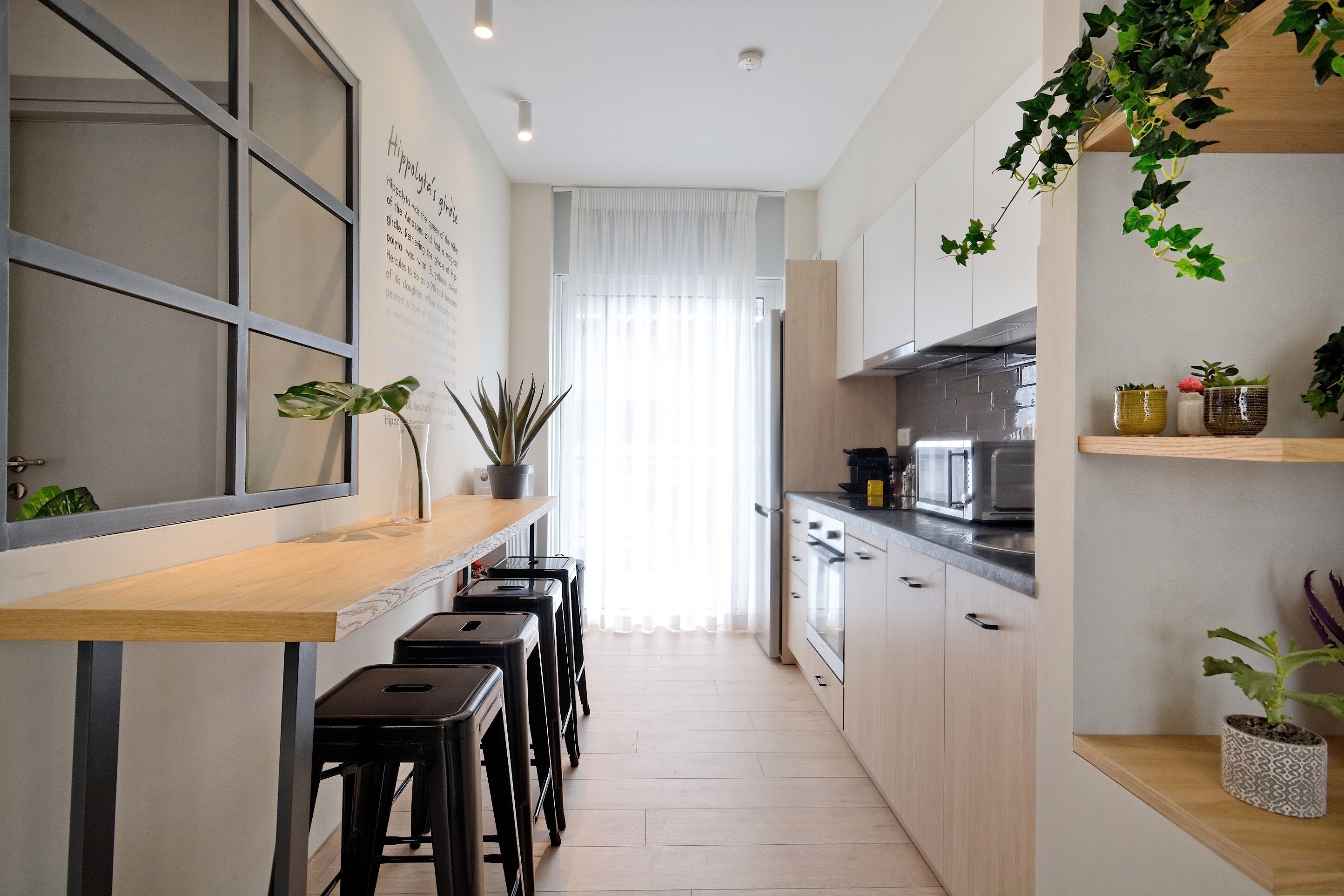 Una cocina moderna con encimera de madera, taburetes negros y plantas en macetas.