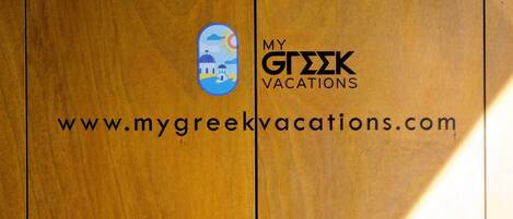 Een houten deur met een logo en de tekst 'MY GREEK VACATIONS' en een website-adres.