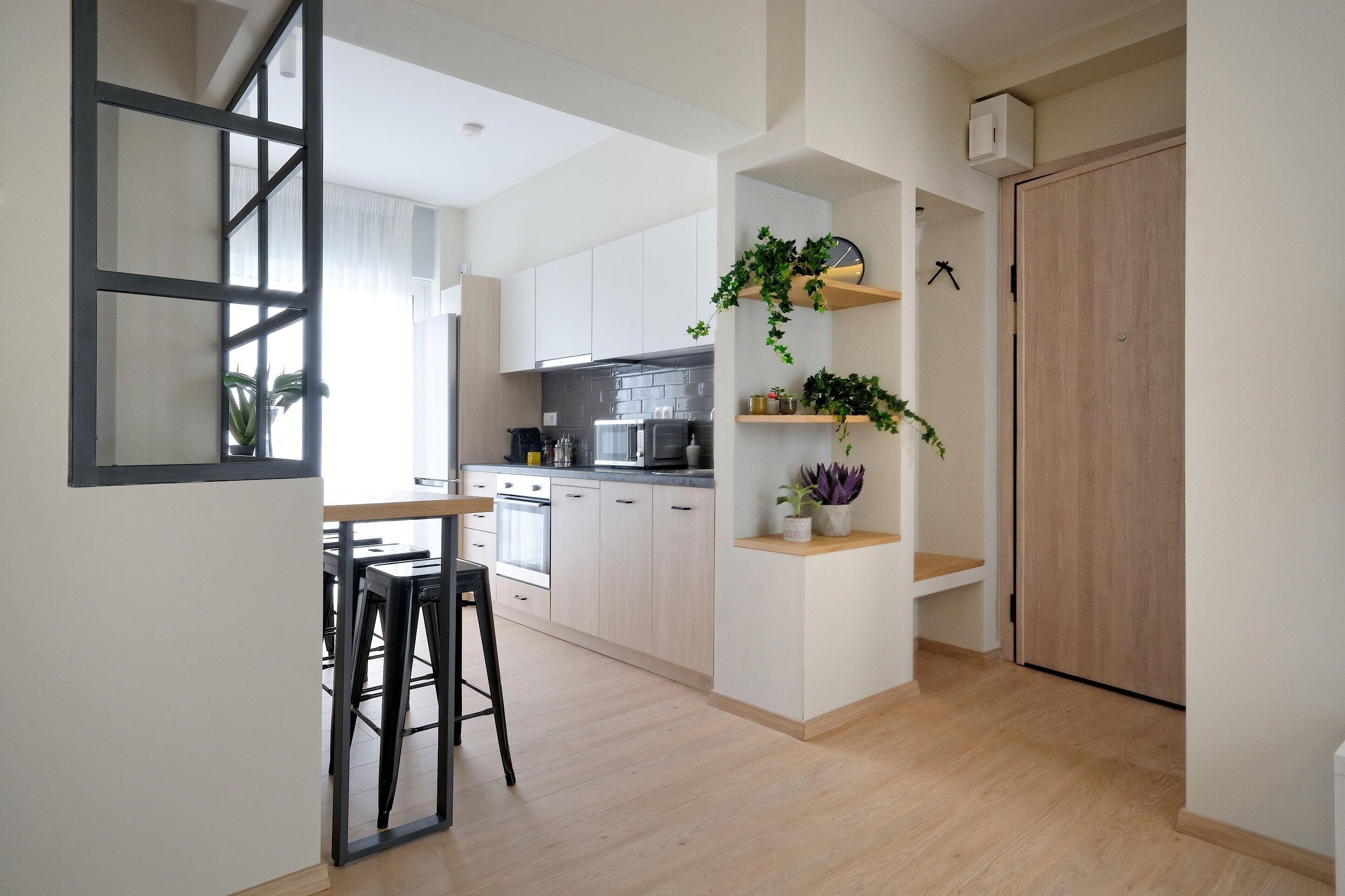 A modern kitchen with white cabinets, a black countertop, and a wooden door.