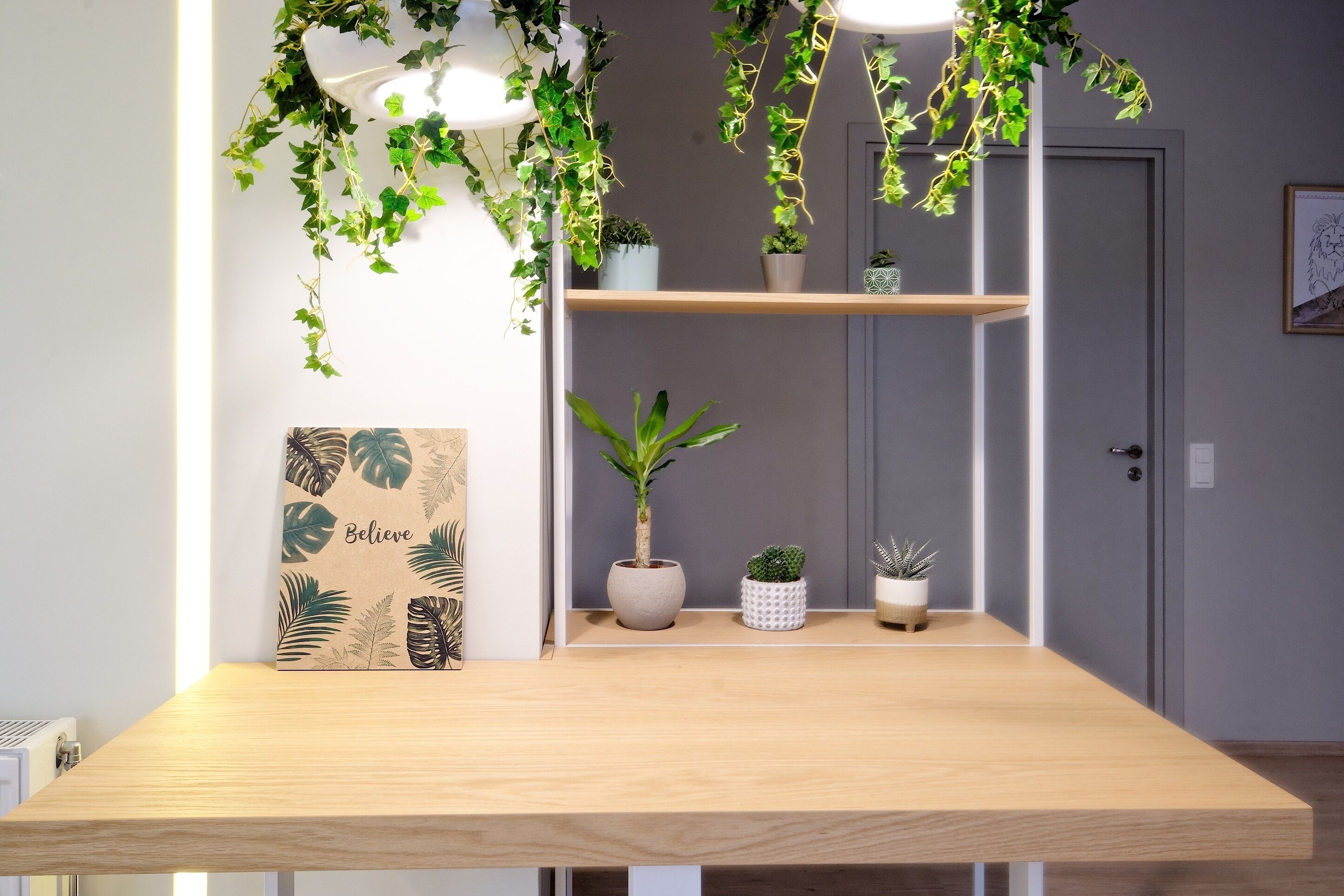 A wooden table with a potted plant and a framed artwork on the wall.