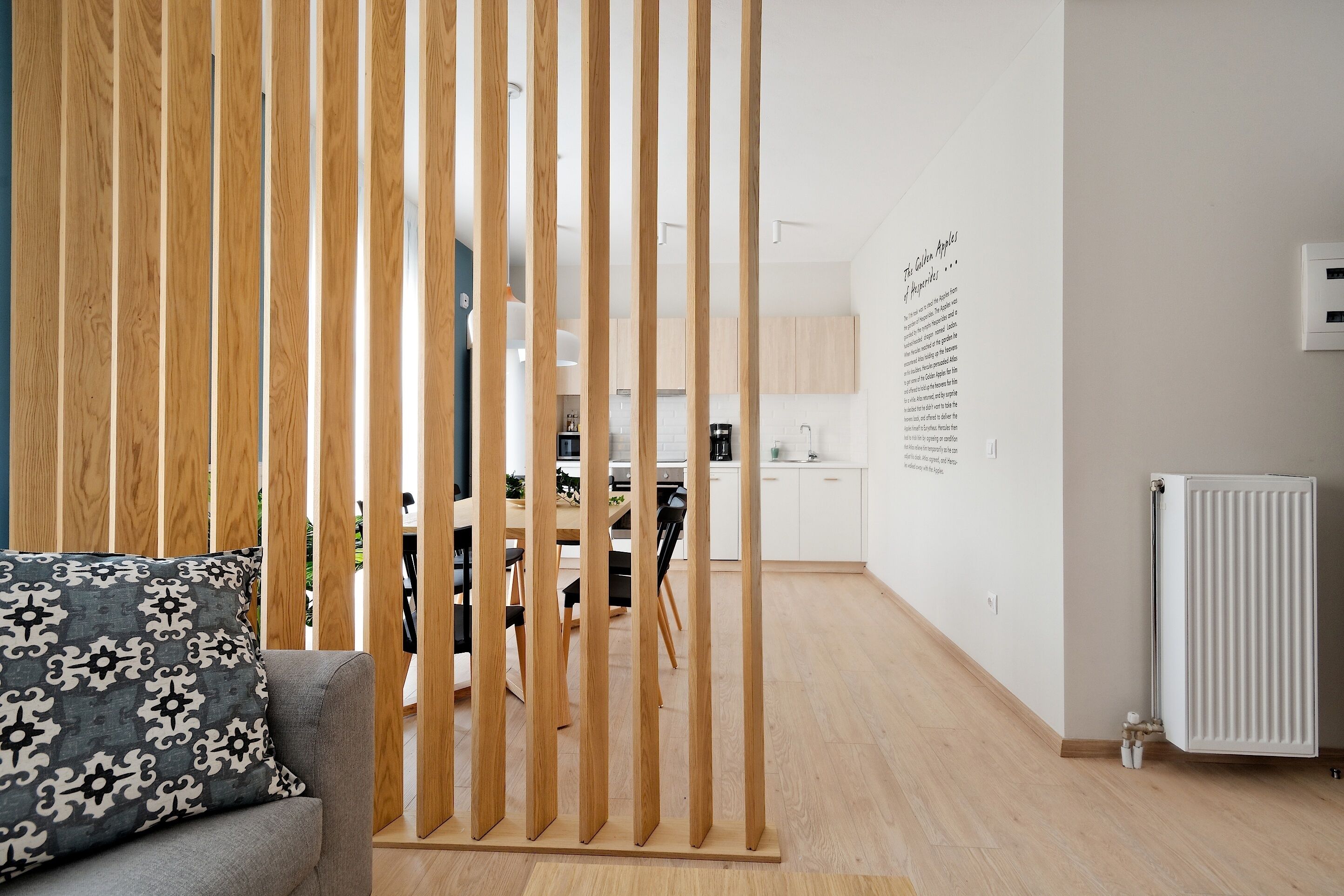 A modern interior with a wooden partition, a dining area, and a kitchen in the background.