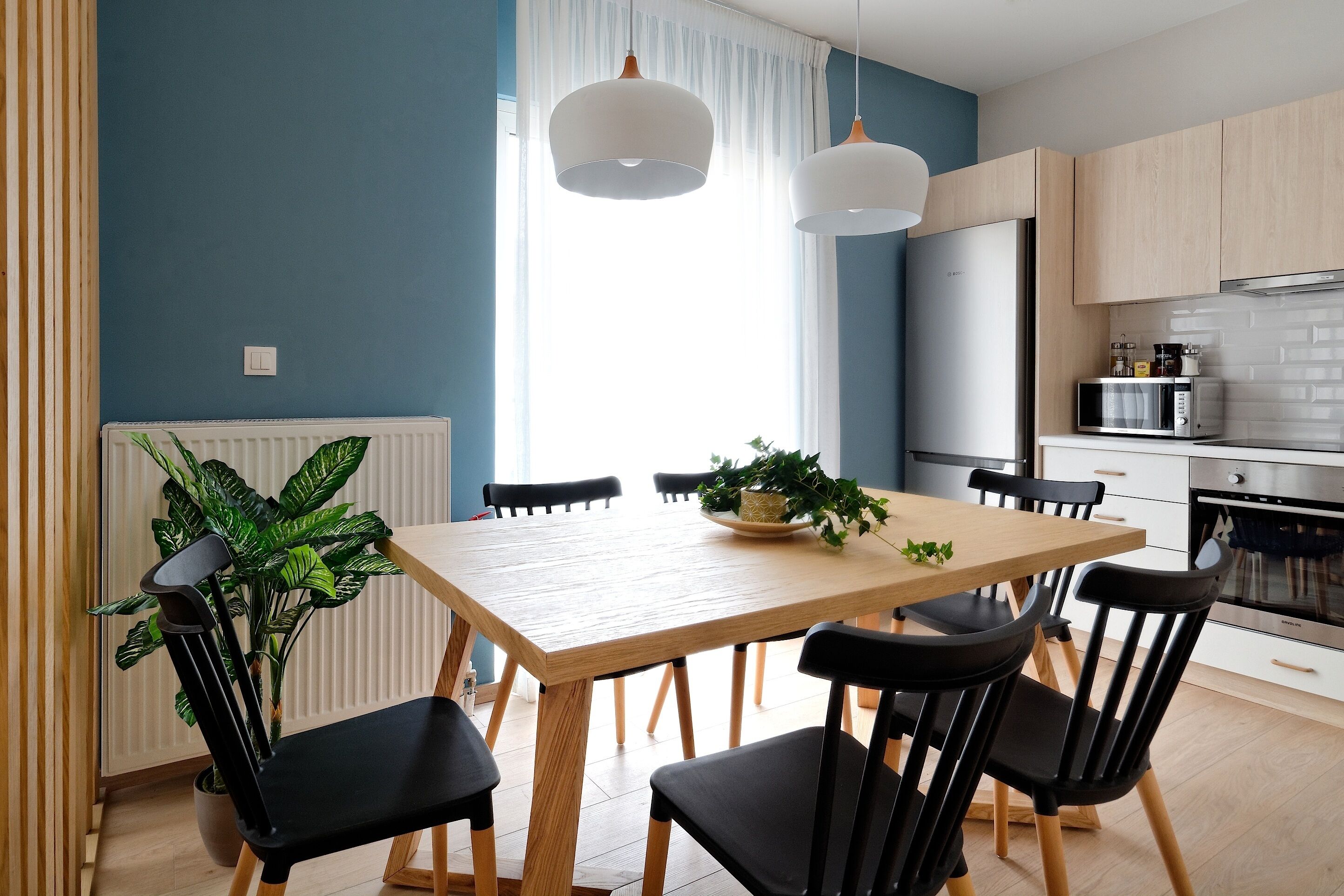 Een moderne keuken met een houten tafel, zwarte stoelen en een magnetron.