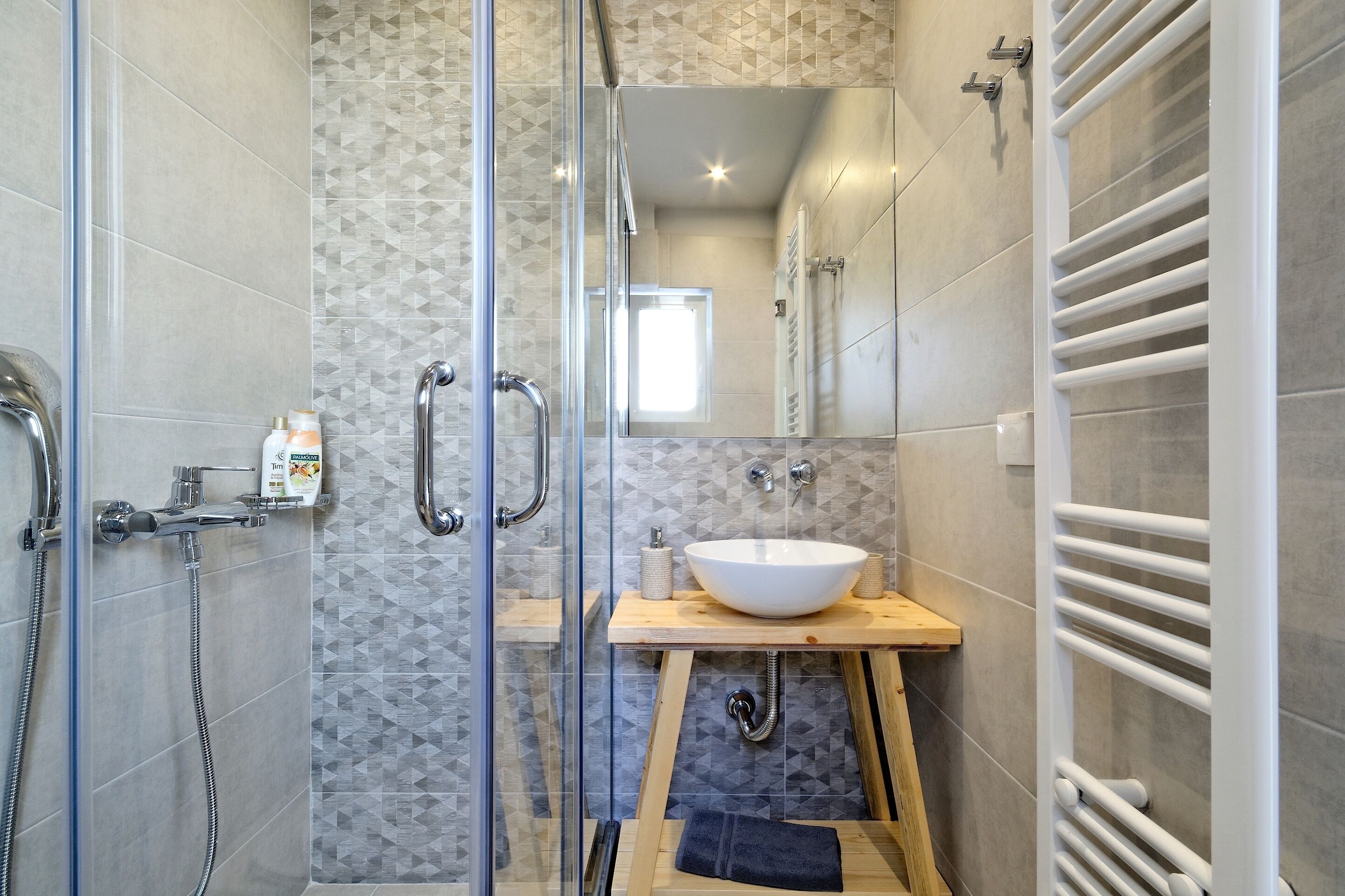 Un baño moderno con cabina de ducha de vidrio, lavamanos blanco y toallero.