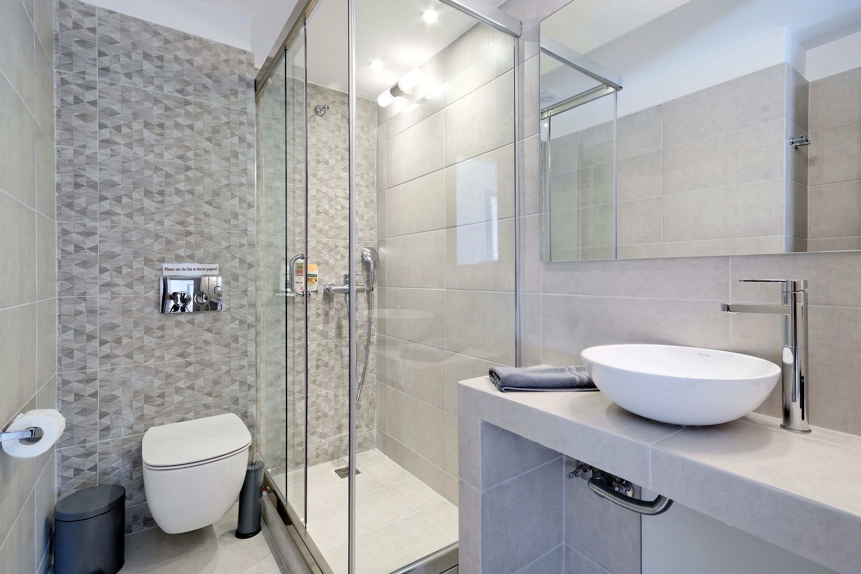 A modern bathroom with a glass shower enclosure, a white sink, and a toilet.