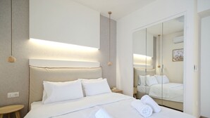 Una habitación de hotel con una cama grande, una mesita de noche, un espejo y una lámpara colgante.