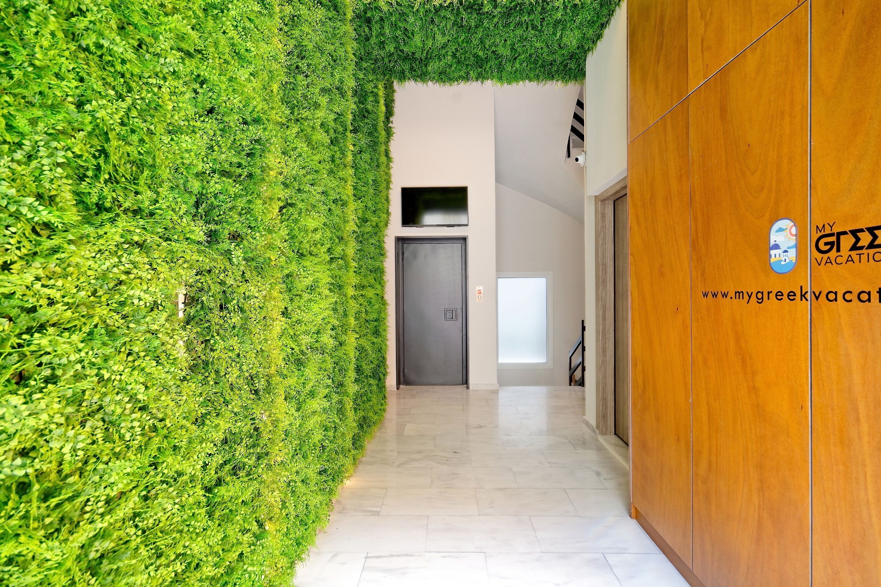 A hallway with a green wall and a wooden panel on the right.