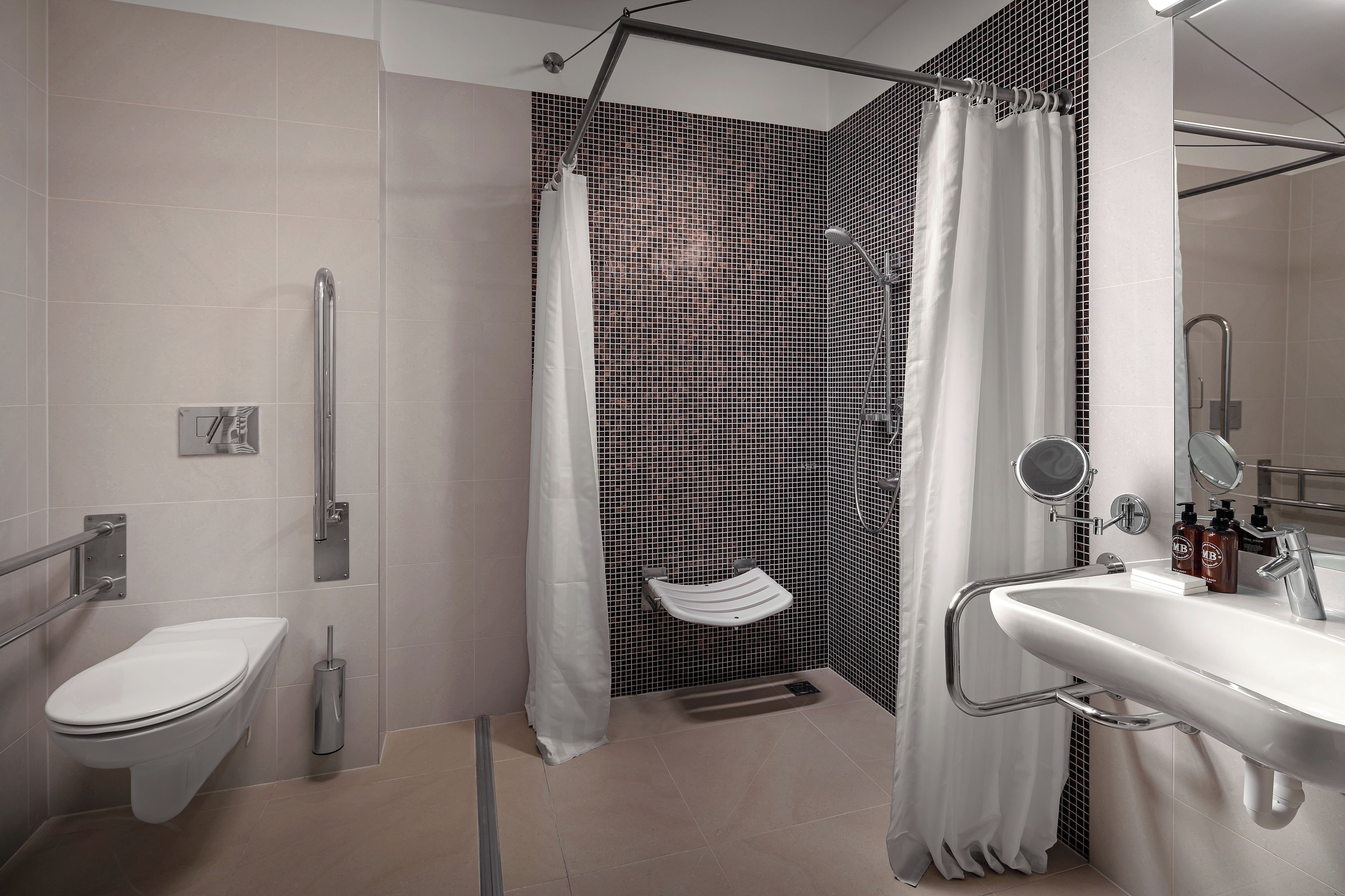 Une salle de bain moderne équipée de toilettes, d’un bidet, d’une douche avec une porte en verre et d’un lavabo avec un miroir.