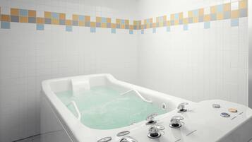 A modern bathroom with a freestanding bathtub, a handheld showerhead, and a control panel with multiple settings.