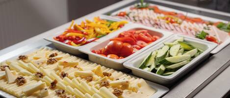 Un bufé con diversas opciones de comida, incluyendo frutas, verduras y queso.
