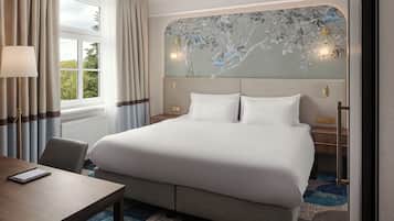A hotel room with a large bed, a desk, a chair, and a view of the outdoors through the window.