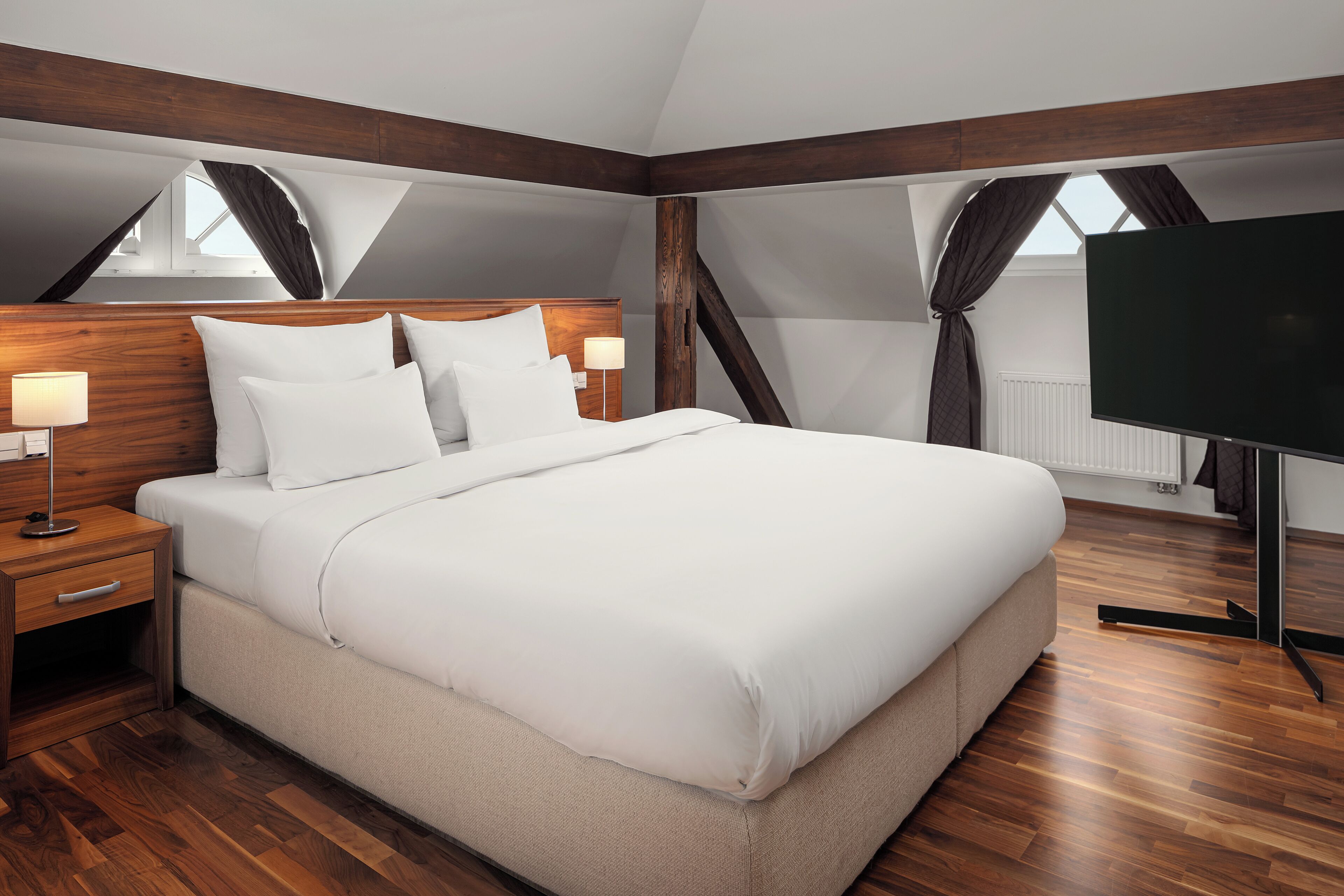 Ein modernes Schlafzimmer mit einem großen Bett, einem Holzkopfende und einem Flachbildfernseher.