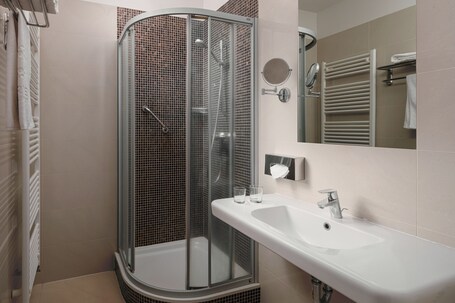 Un baño moderno con ducha acristalada, lavabo blanco y espejo.
