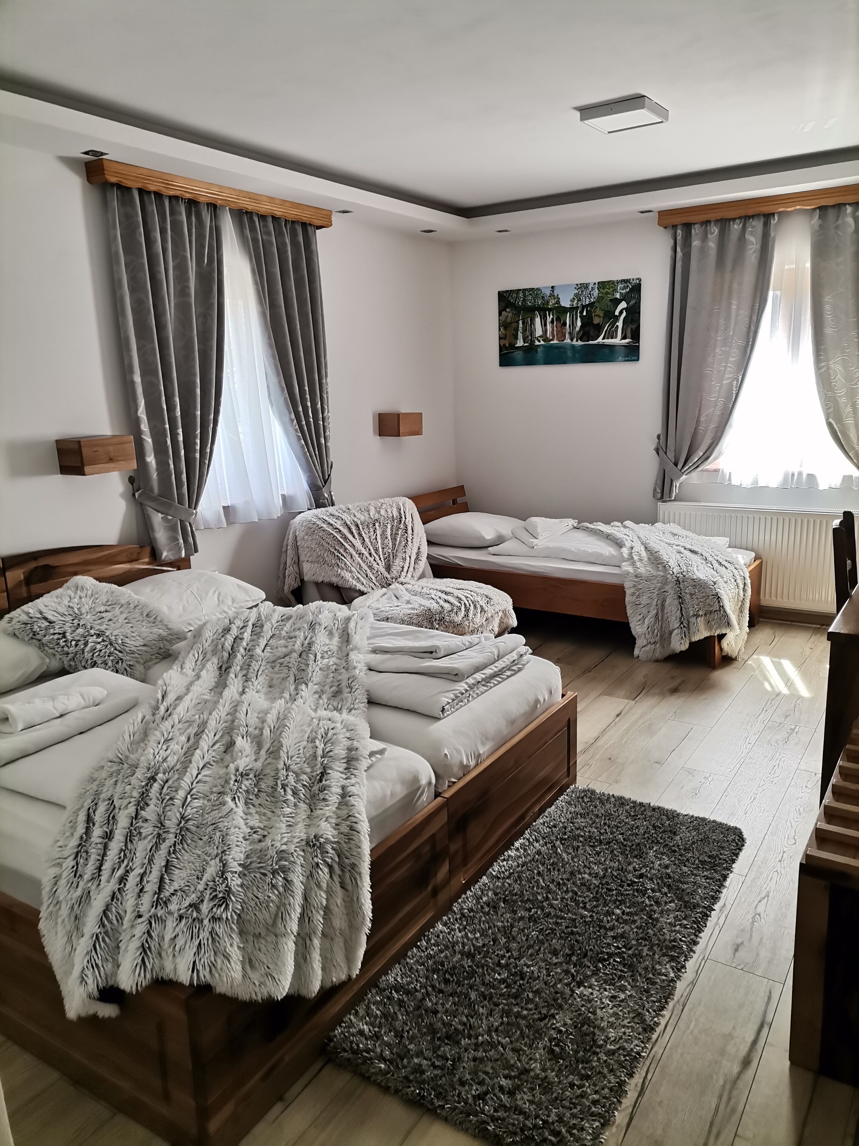 Un dormitorio con tres camas, un tapete grande y un cuadro en la pared.