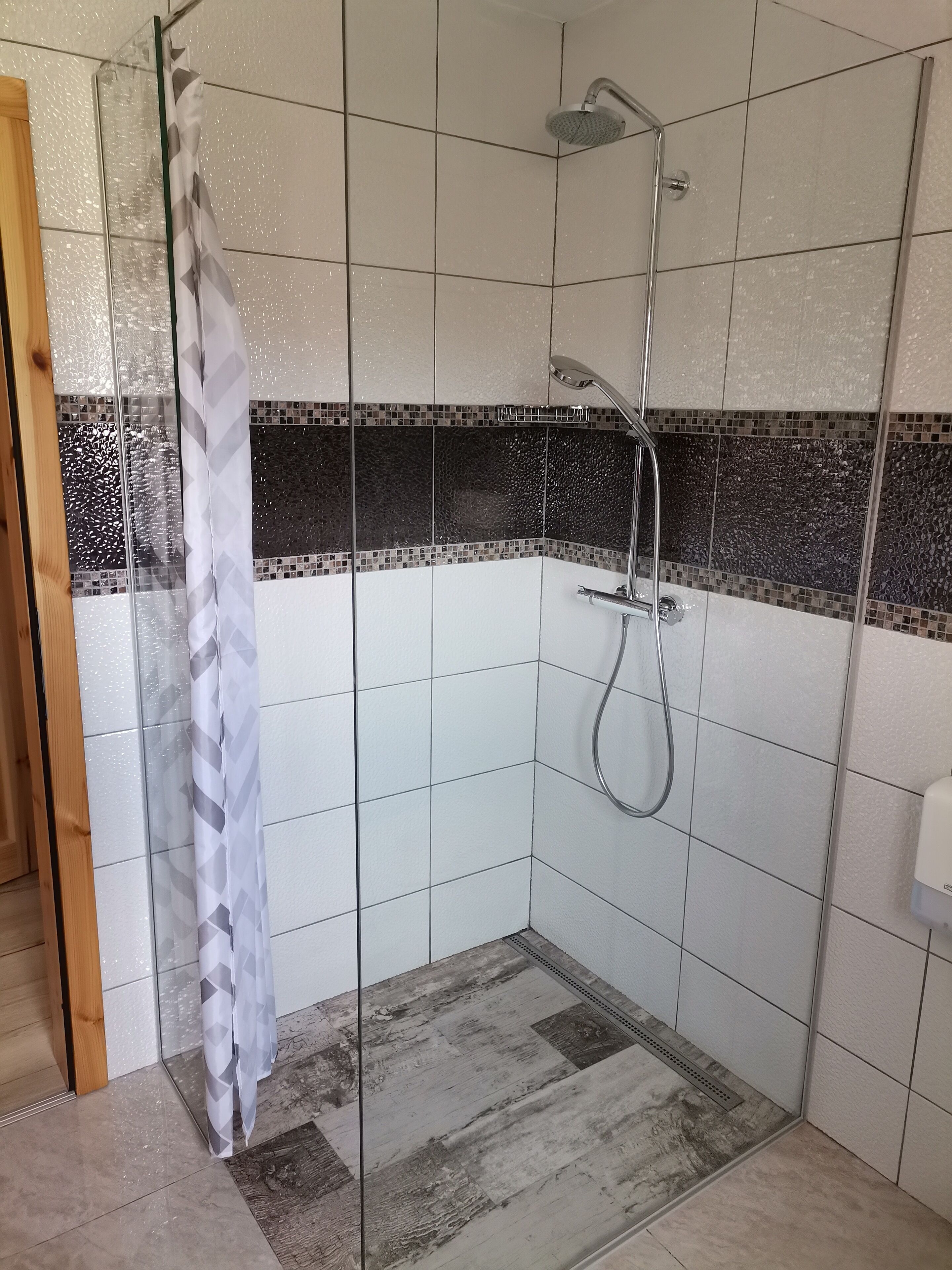 A shower area with a glass door, tiled walls, and a showerhead.