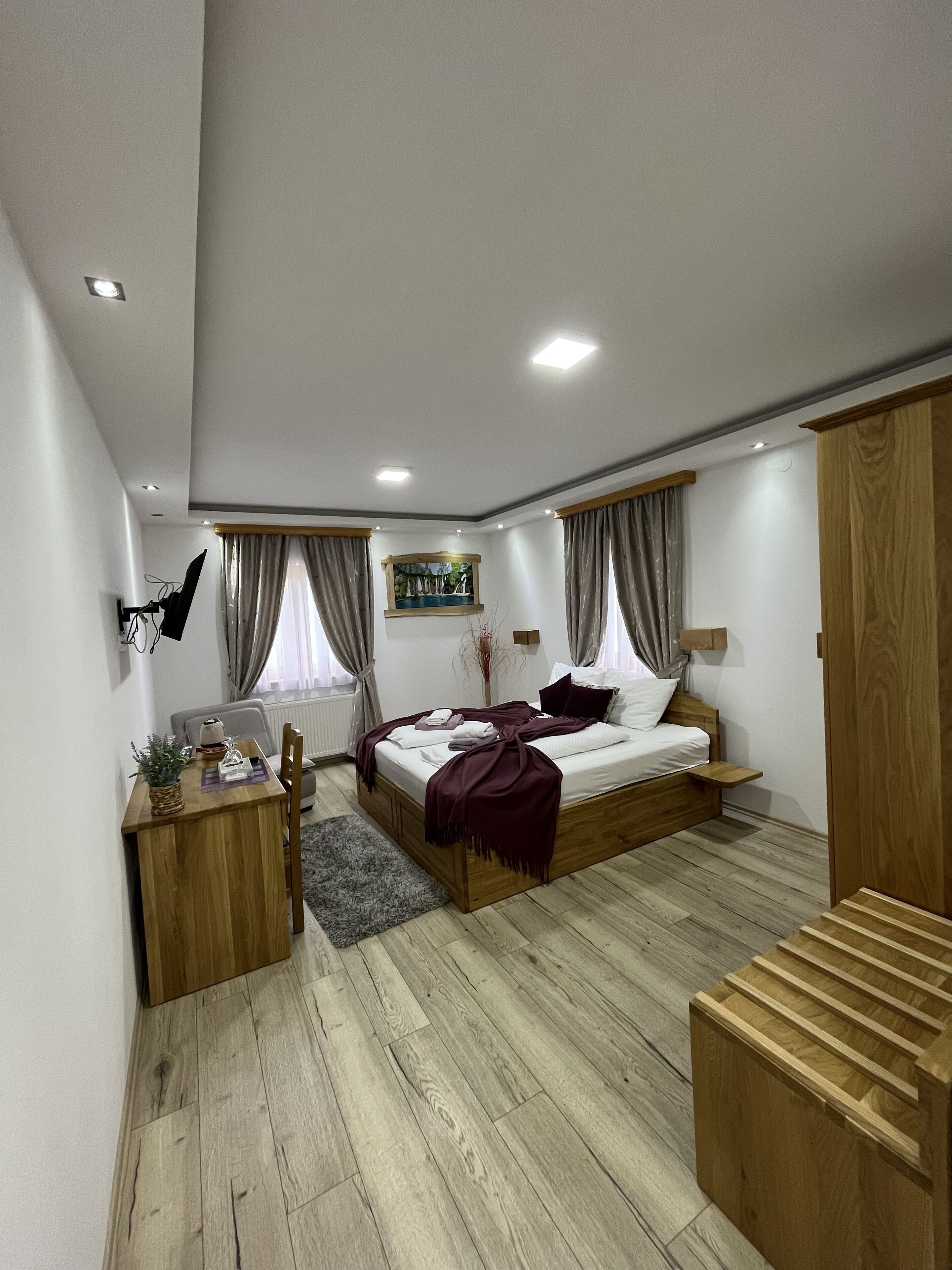 A modern bedroom with a wooden bed, a desk, and a small seating area.