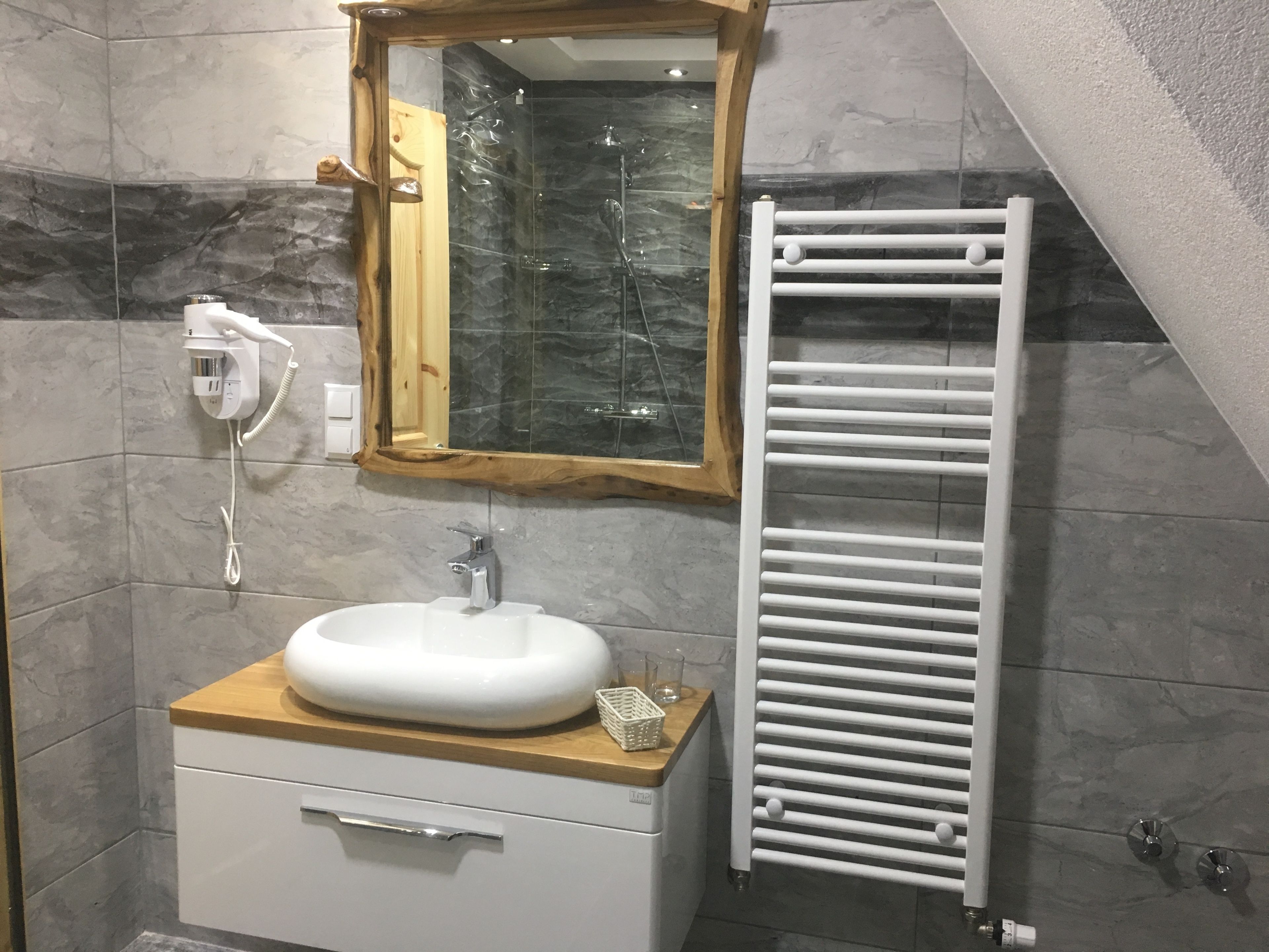 Ein Badezimmer mit einem Holzbadezimmer, einem weißen Waschbecken, einem Spiegel und einem weißen Handtuchhalter.