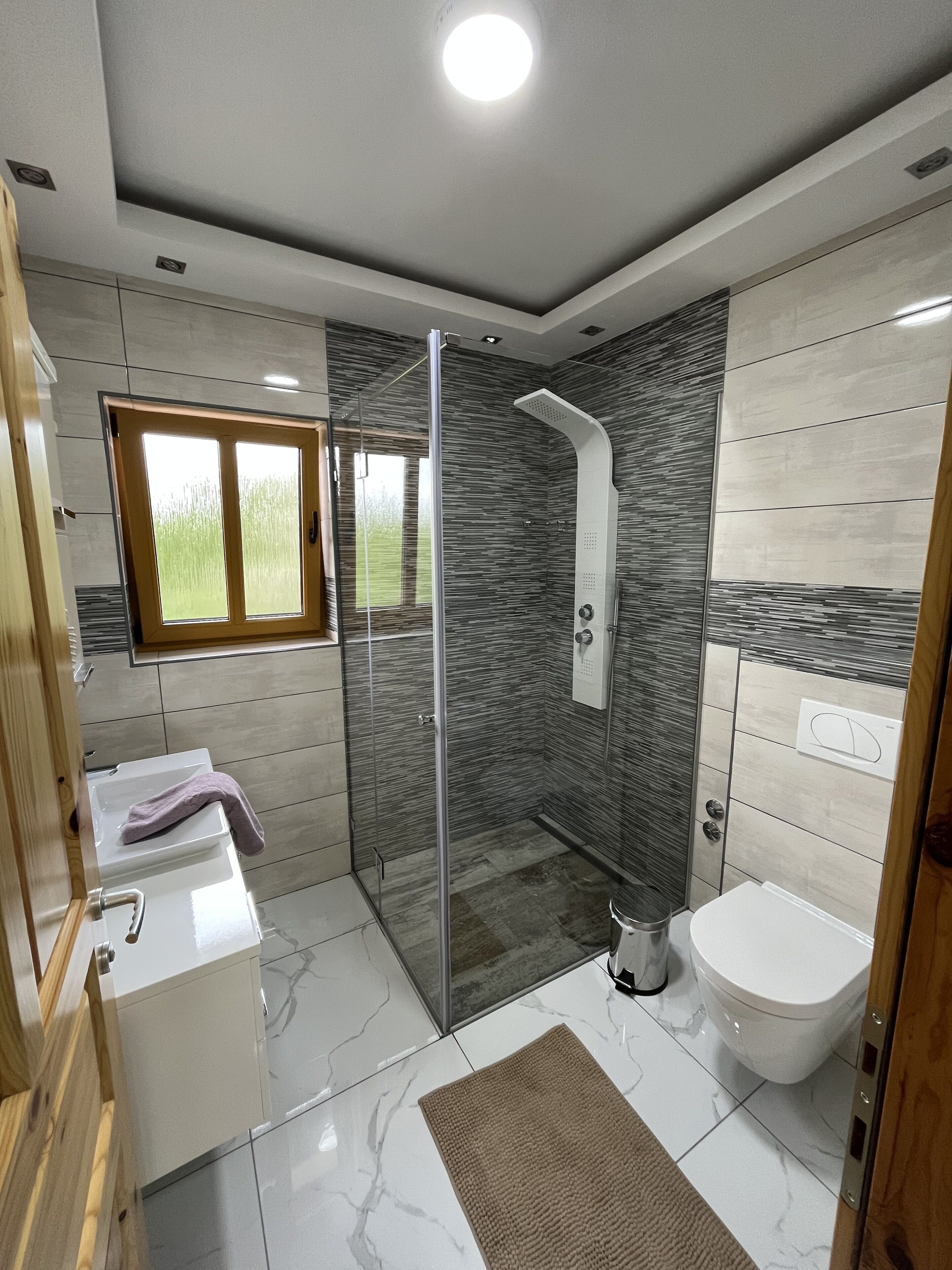 Un bany modern amb dutxa de vidre, un vàter i un lavabo amb una tovallola.