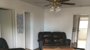 Ein Wohnzimmer mit einem schwarzen Ledersofa, einem Holztisch und einem Deckenventilator.