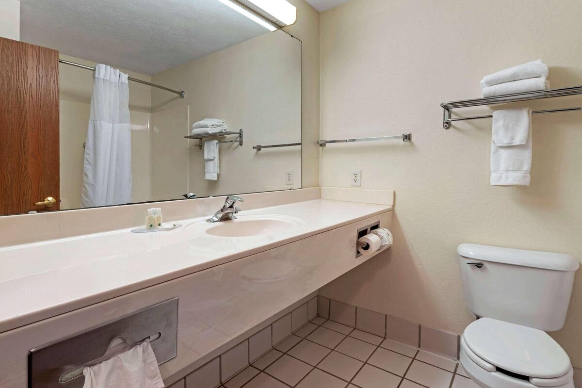 A bathroom with a sink, mirror, towel rack, and toilet.