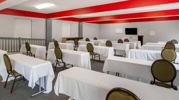 A conference room with multiple tables and chairs, a whiteboard, and a television on the wall.