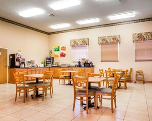 A dining area with multiple tables and chairs, a kitchen counter with appliances, and decorative wall art. - Surestay Best Western Obetz Rickenbacker Airport (Columbus)