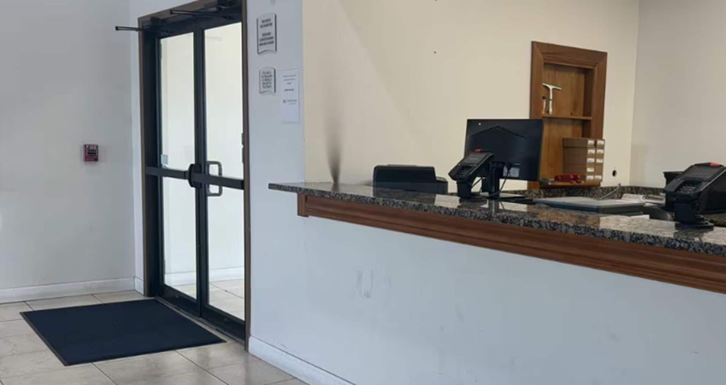 A reception area with a glass door, a reception desk, a telephone, and a small storage cabinet.