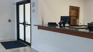 A reception area with a glass door, a reception desk, a telephone, and a small storage cabinet.