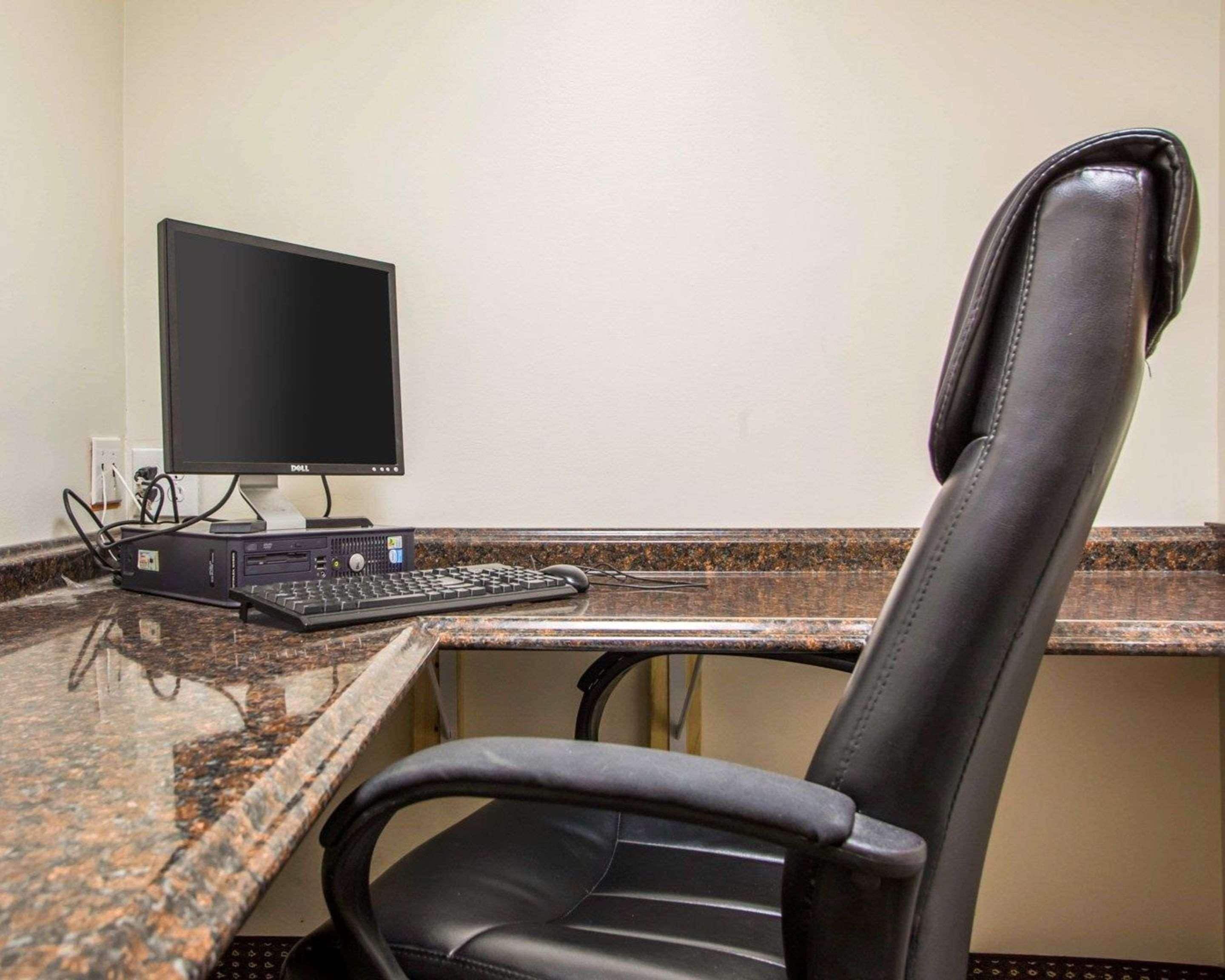 Un espace de travail dans un hôtel, équipé d’un ordinateur de bureau, d’un clavier et d’un fauteuil en cuir.