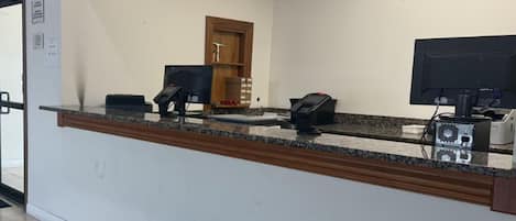 A reception desk with a computer, telephone, and a small cabinet.
