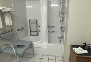 A bathroom with a toilet, shower, and bathtub. There is a grab bar, a towel rack, and a wooden cabinet with toiletries. - Surestay Best Western Obetz Rickenbacker Airport (Columbus)