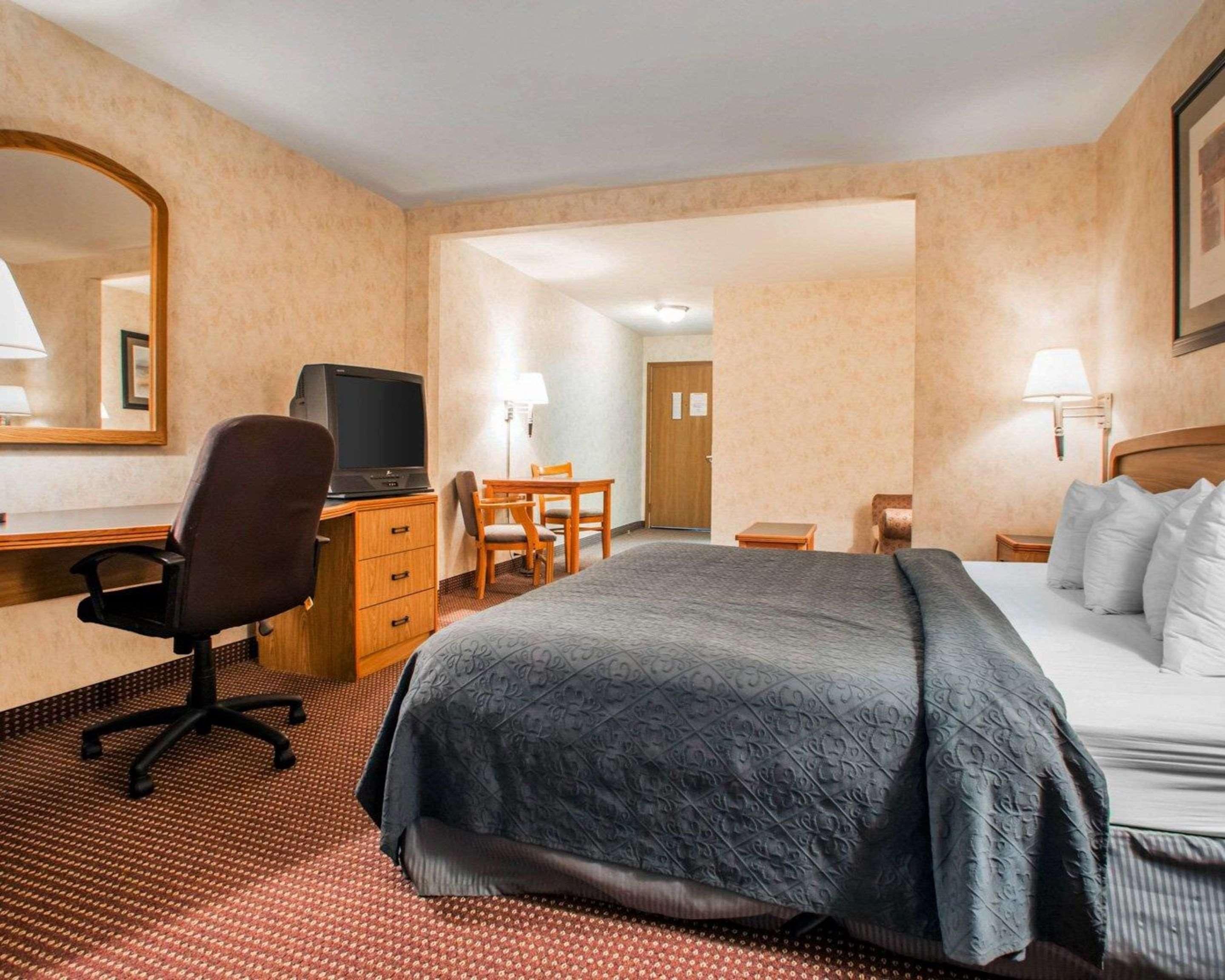 Une chambre d’hôtel comprenant un lit, un bureau avec une chaise, une télévision et un miroir.