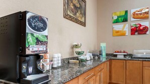 A coffee machine with options for coffee, hot water, and decaf, a bowl of fruit, and a waffle plate on a granite countertop in a kitchen. - Surestay Best Western Obetz Rickenbacker Airport (Columbus)