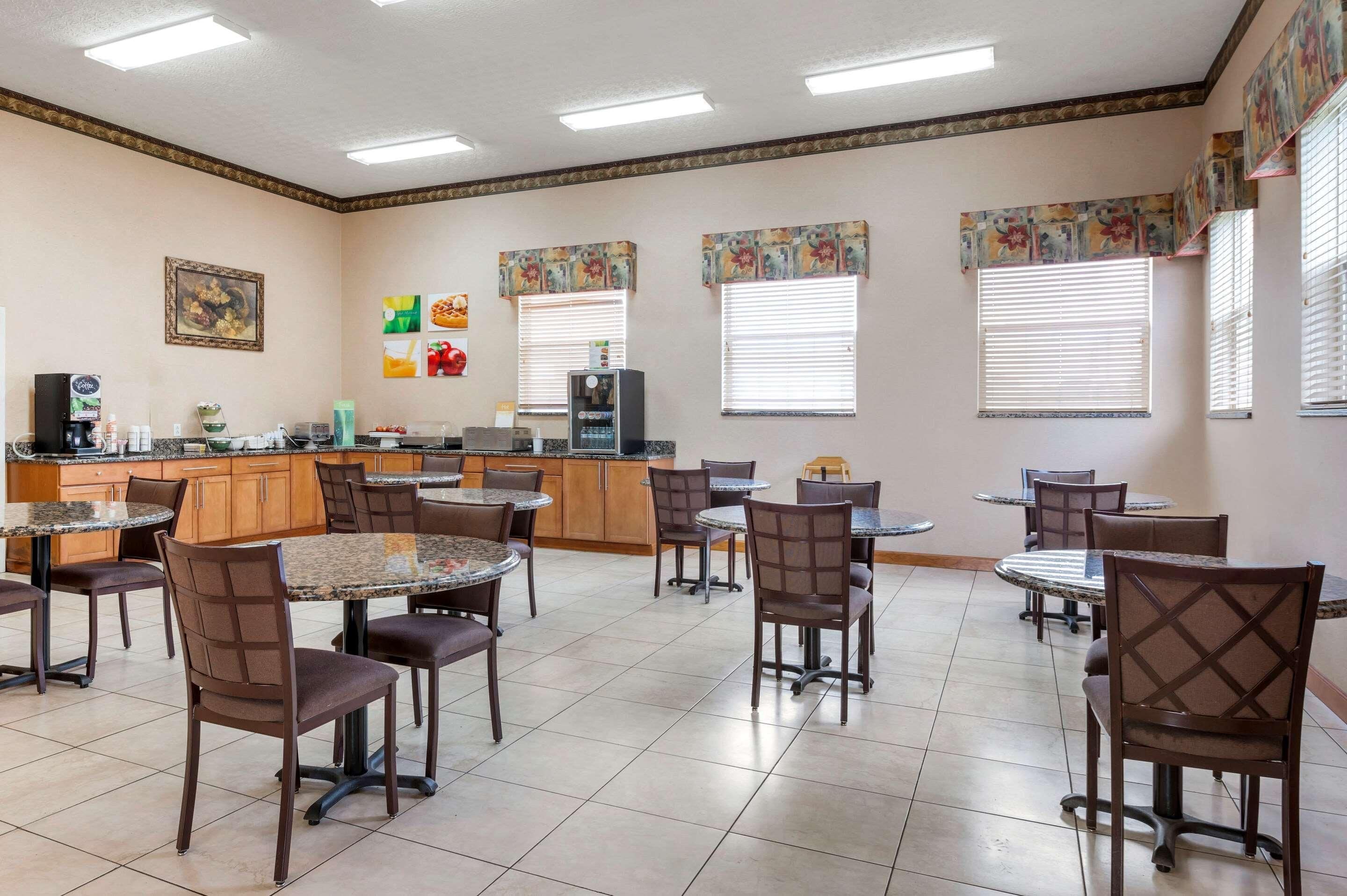 A dining area with multiple tables and chairs, a kitchen area with appliances, and decorative wall art.