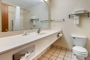 Ein Badezimmer mit Waschbecken, Spiegel, Handtuchhalter und Toilette.
