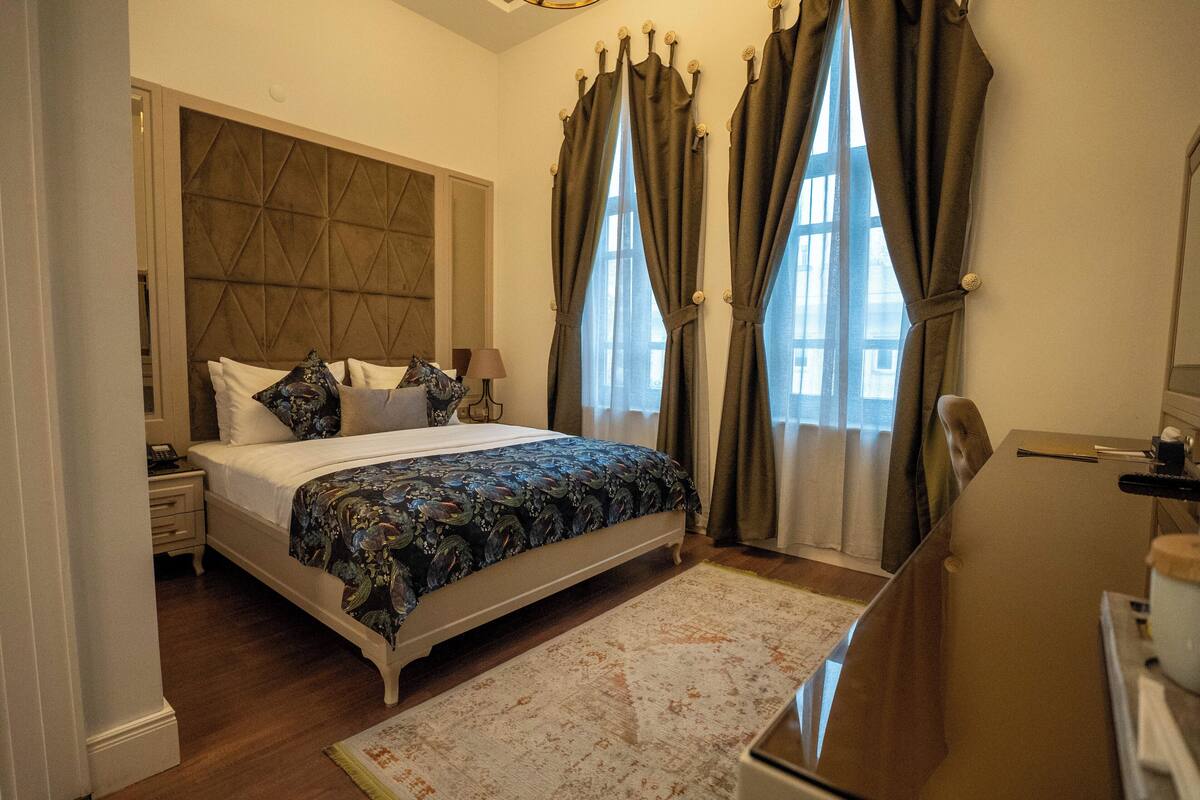 A bedroom with a bed, bedside table, lamp, and curtains.