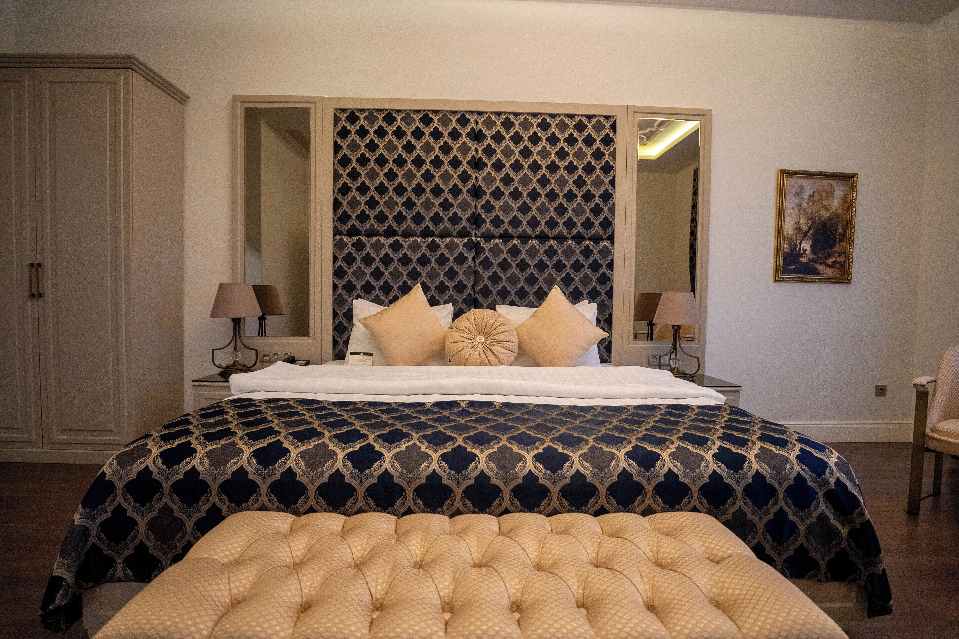 Un dormitorio con una cama grande, un cabecero acolchado y una mesita de noche con lámparas.