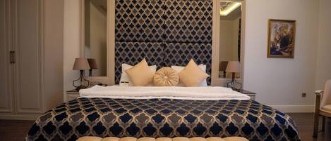 Un dormitorio con una cama grande, un cabecero acolchado y una mesita de noche con lámparas.