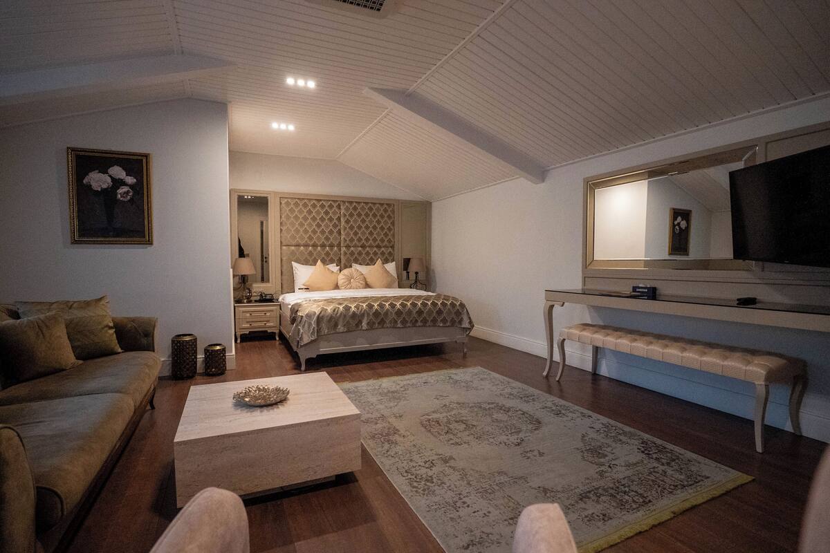 A bedroom with a bed, bedside table, lamp, and a large mirror.