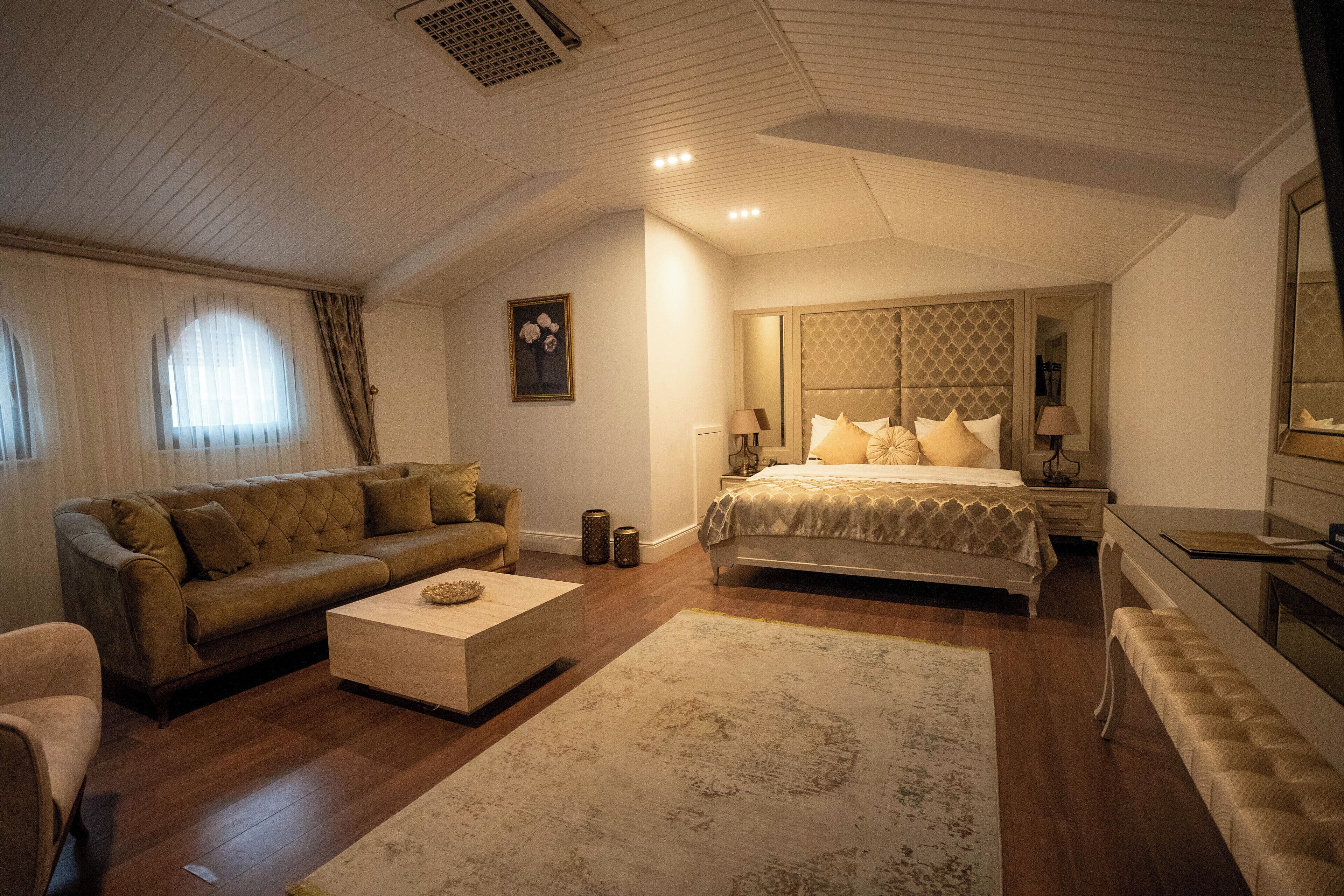 Een slaapkamer met een groot bed, een bank, een bijzettafeltje en een spiegel.