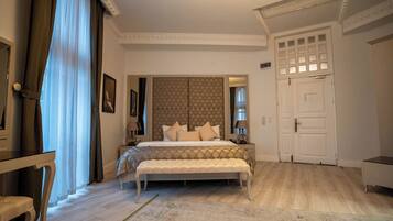 A bedroom with a large bed, a bench, a desk, and a wardrobe.
