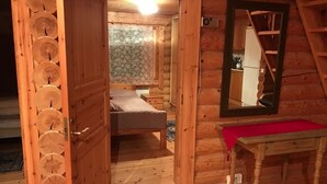 A wooden cabin room with a bed, a table, and a mirror. - Cottage H62 Ruokolahti (Ruokolahti)