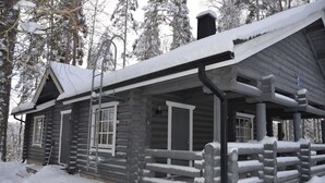 A log cabin with a porch, surrounded by snow-covered trees. - Cottage H62 Ruokolahti (Ruokolahti)