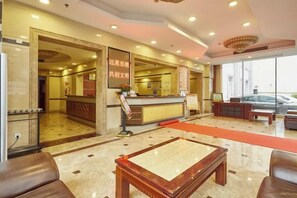 A hotel lobby with a reception desk, seating area, and a view of the street. - Jinxiu Hotel (Shanghai)