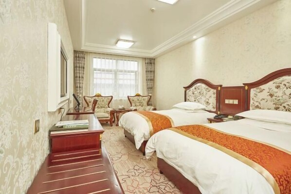 Une chambre d’hôtel avec deux lits, un bureau, une chaise et une fenêtre avec des rideaux.
